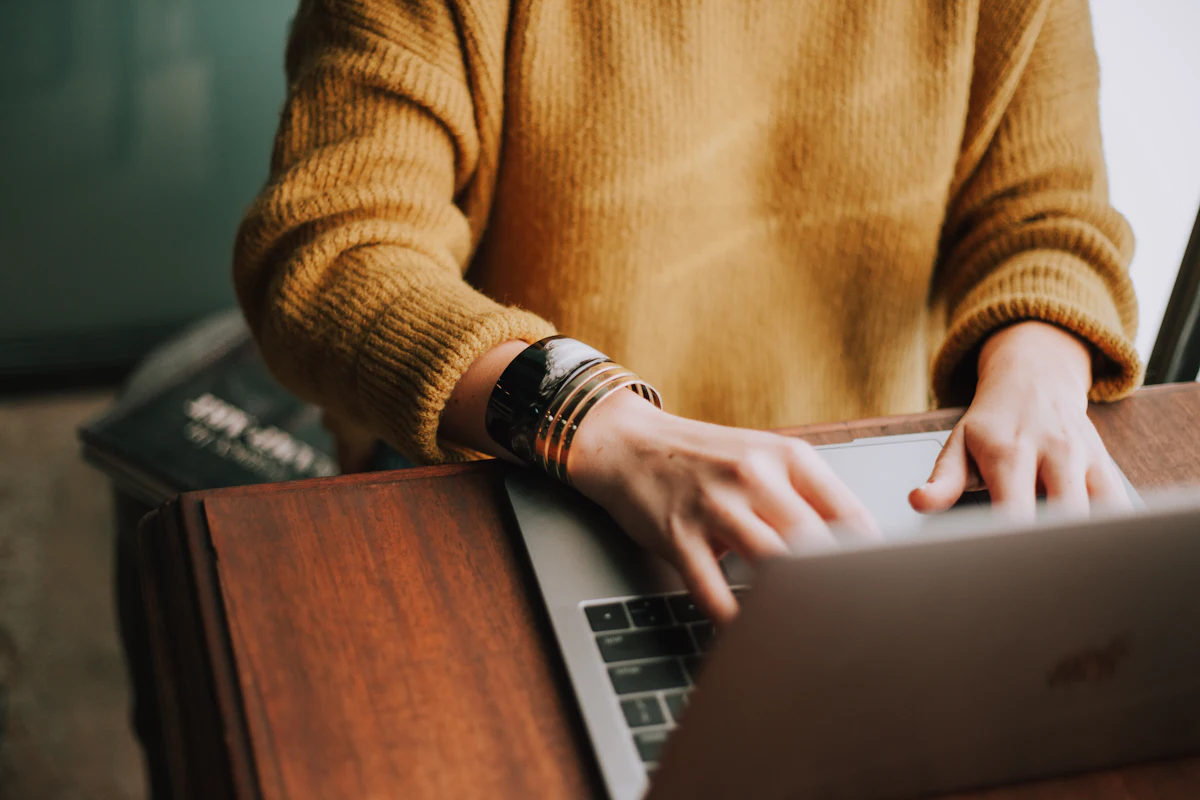 Person tippt an einem Laptop-Bildschirm mit Text